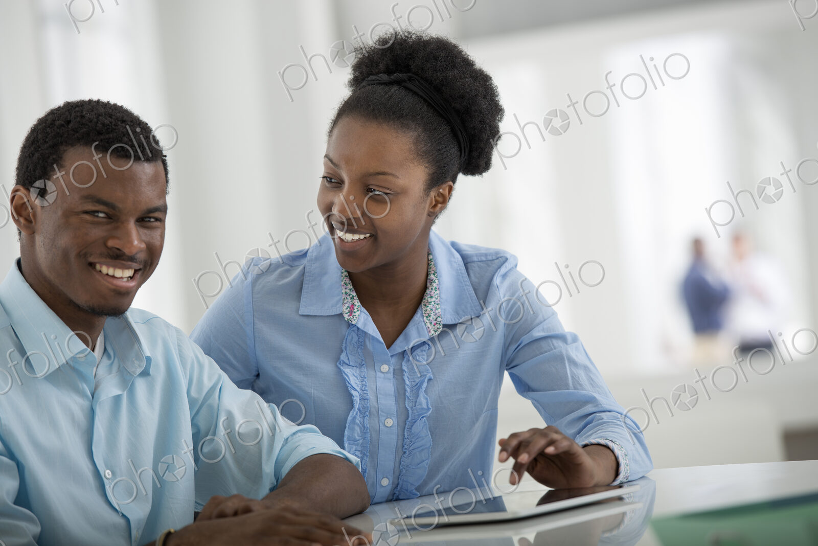 A fresh white building interior, flooded with light. A man and woman sitting side by…
