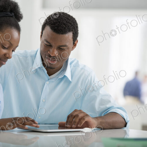 A fresh white building interior, flooded with light. A man and woman sitting side by…