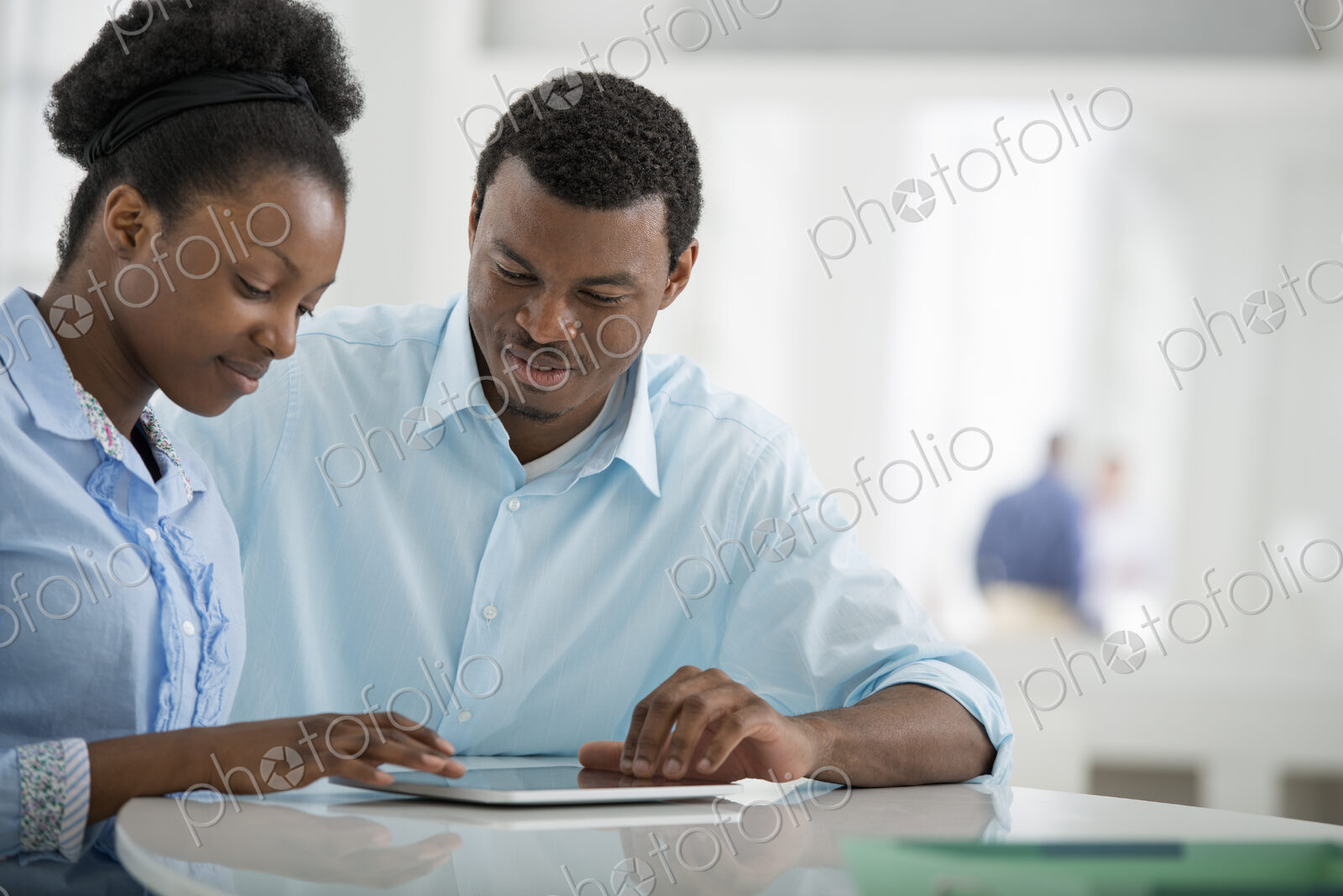 A fresh white building interior, flooded with light. A man and woman sitting side by…