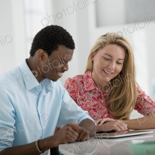 A fresh white building interior, flooded with light. A man and woman sitting side by…