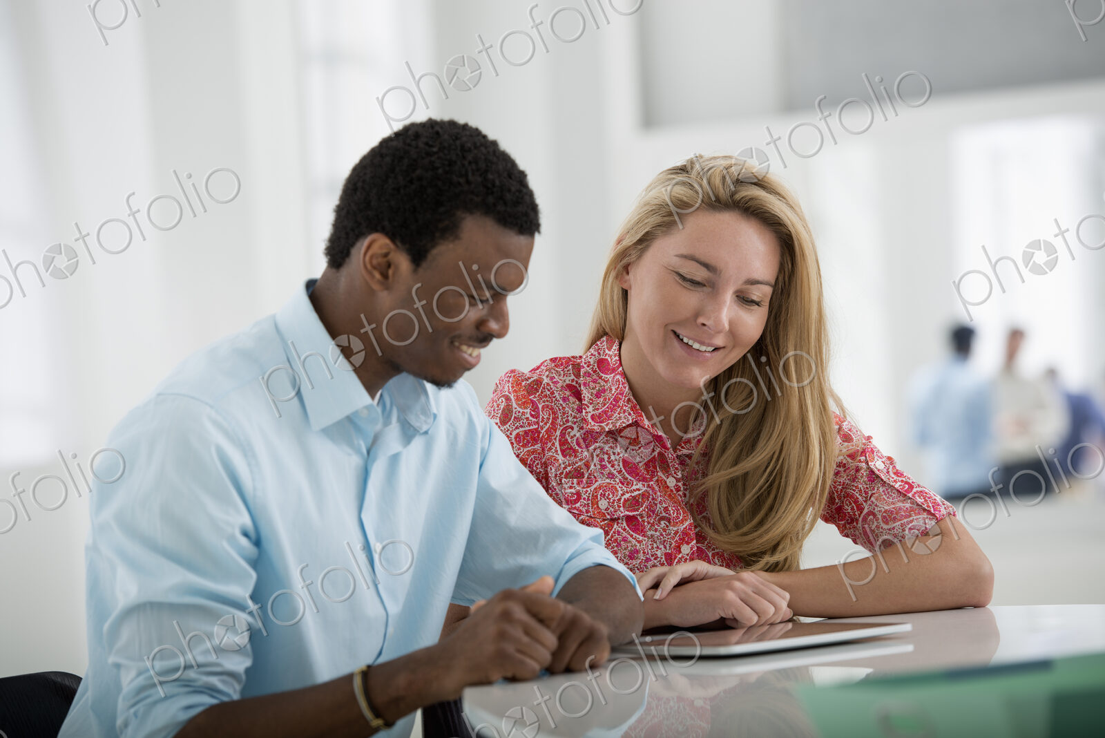 A fresh white building interior, flooded with light. A man and woman sitting side by…