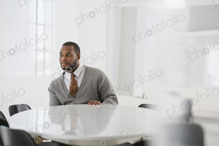 A fresh white building interior, flooded with light. A man in a business suit at a…