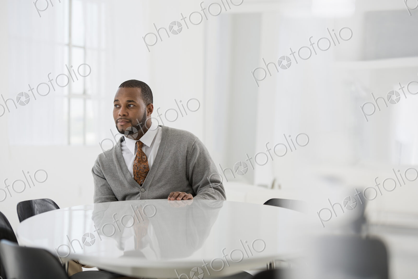 A fresh white building interior, flooded with light. A man in a business suit at a…