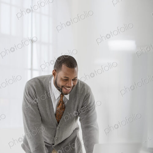 A fresh white building interior, flooded with light. A man in a business suit at a…