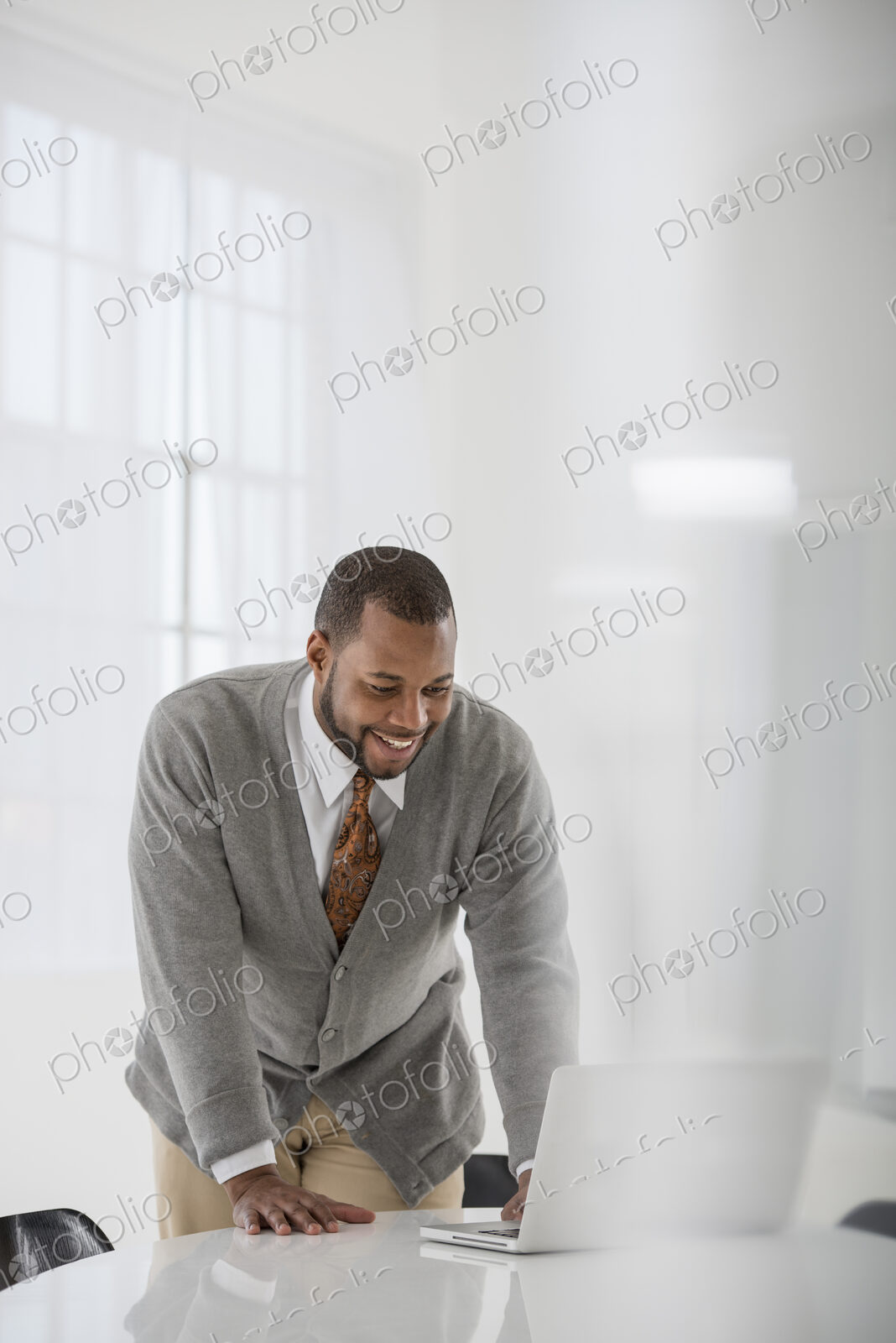 A fresh white building interior, flooded with light. A man in a business suit at a…