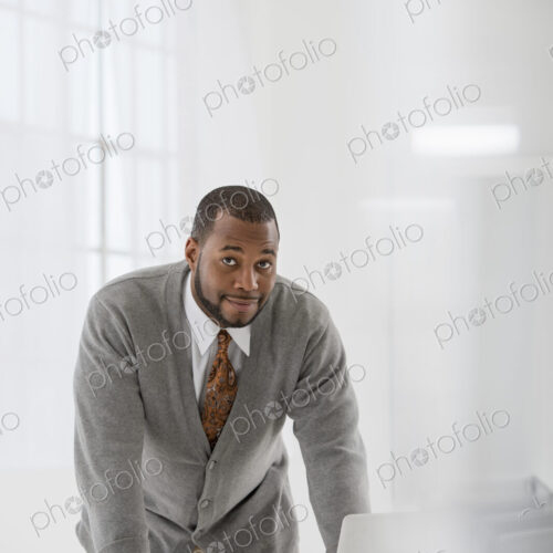 A fresh white building interior, flooded with light. A man in a business suit at a…
