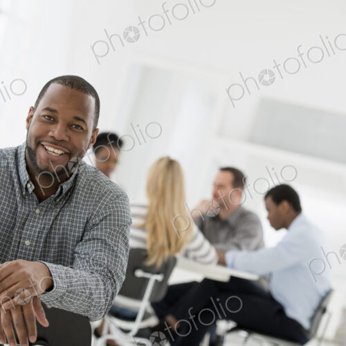A fresh white building interior, flooded with light. A man seated separately from a… A fresh white building interior, flooded with light. A man seated separately from a…