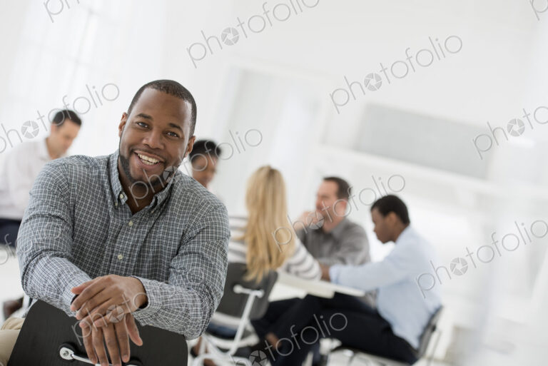 A fresh white building interior, flooded with light. A man seated separately from a…