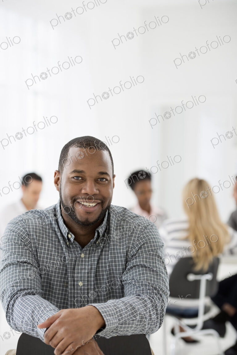 A fresh white building interior, flooded with light. A man seated separately from a…