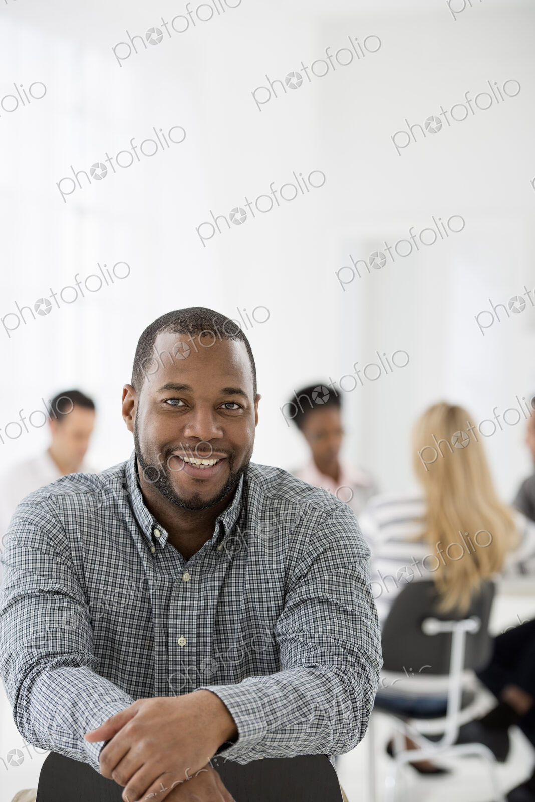 A fresh white building interior, flooded with light. A man seated separately from a…