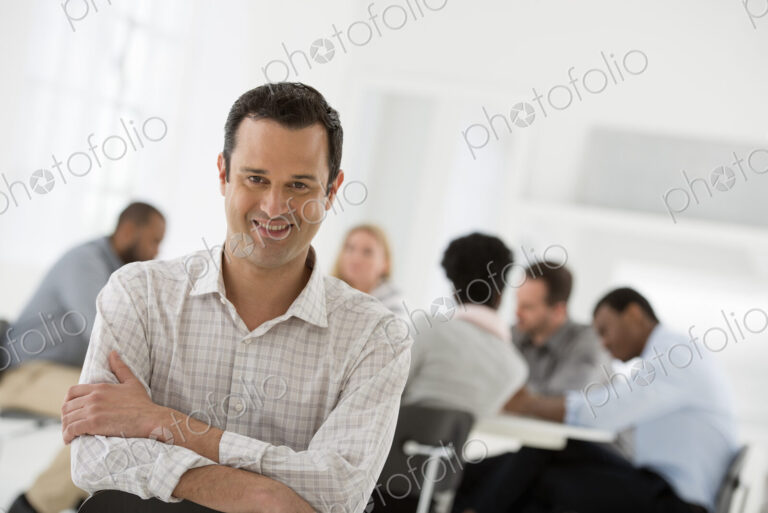 A fresh white building interior, flooded with light. A man seated separately from a…