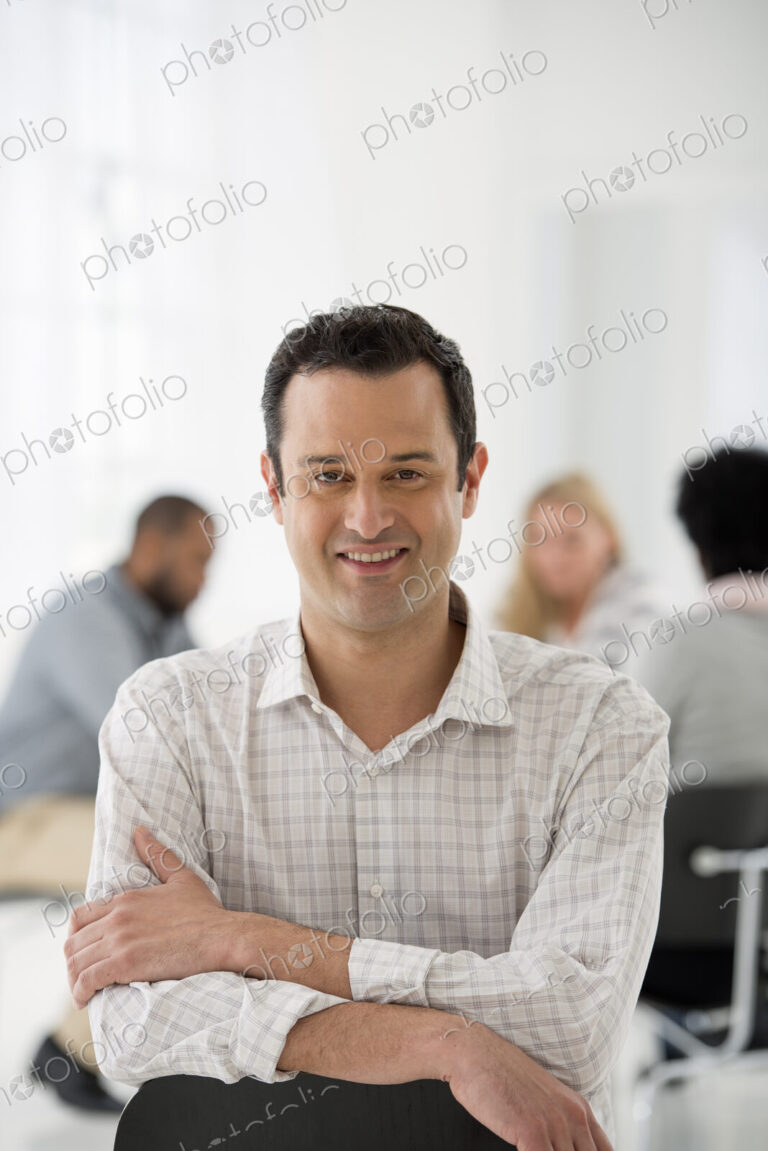 A fresh white building interior, flooded with light. A man seated separately from a…
