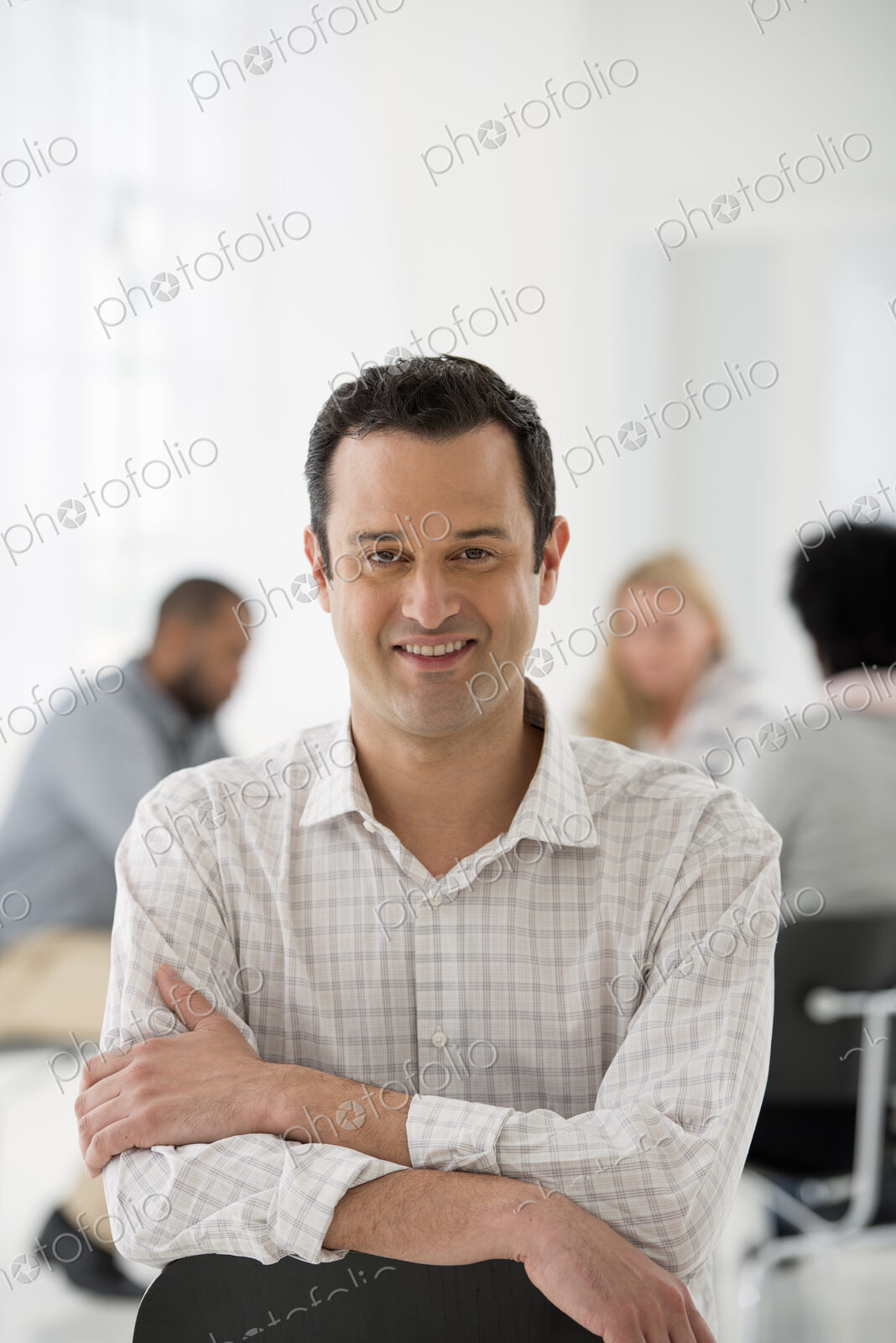 A fresh white building interior, flooded with light. A man seated separately from a…