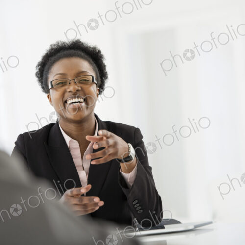 A fresh white building interior, flooded with light. A woman in a black suit jacket…