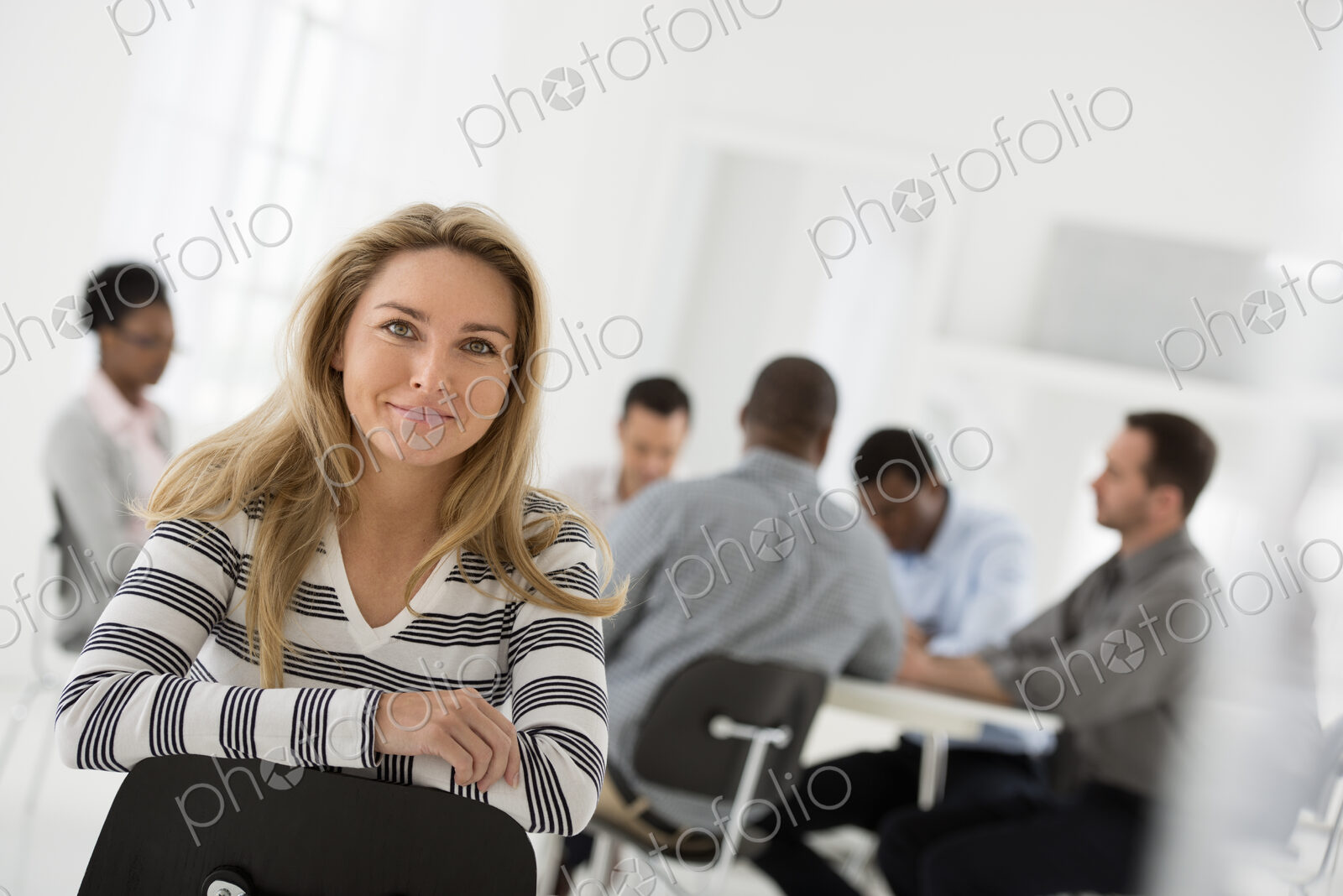 A fresh white building interior, flooded with light. A woman in a striped shirt seated…