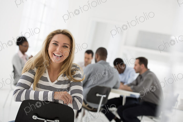 A fresh white building interior, flooded with light. A woman in a striped shirt seated…