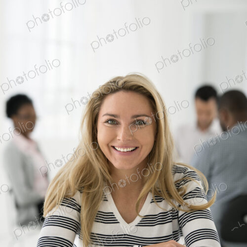 A fresh white building interior, flooded with light. A woman in a striped shirt seated… A fresh white building interior, flooded with light. A woman in a striped shirt seated…