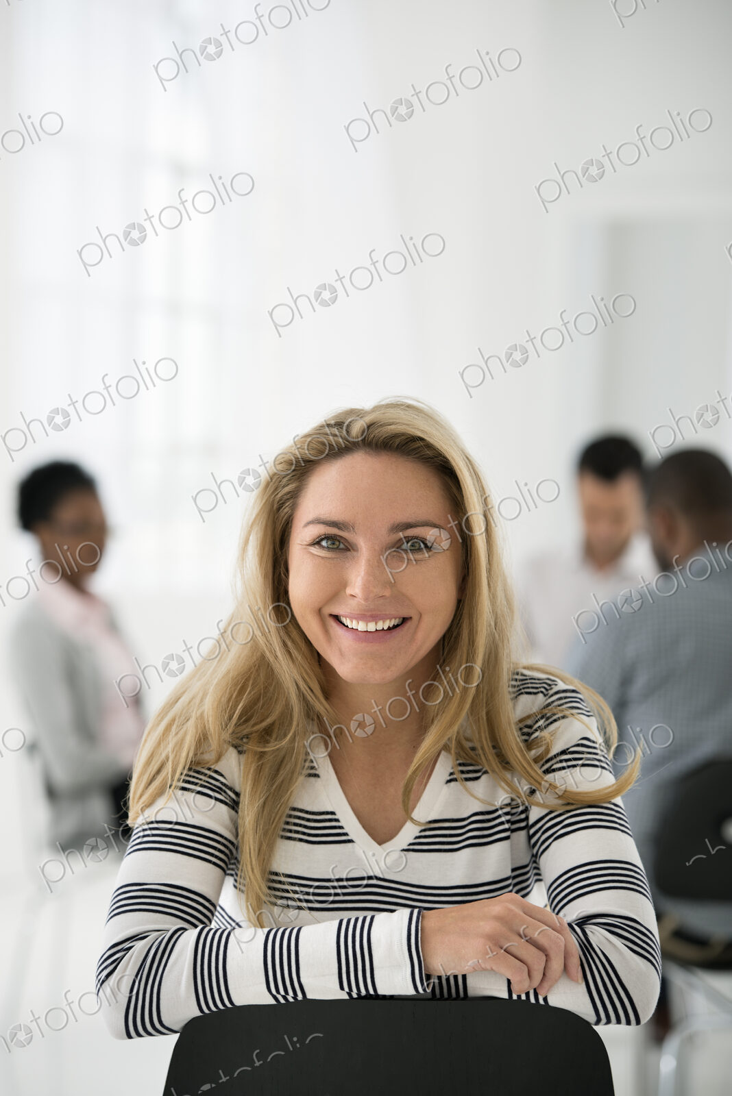 A fresh white building interior, flooded with light. A woman in a striped shirt seated…