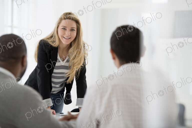 A fresh white building interior, flooded with light. A woman leaning on a tabletop…