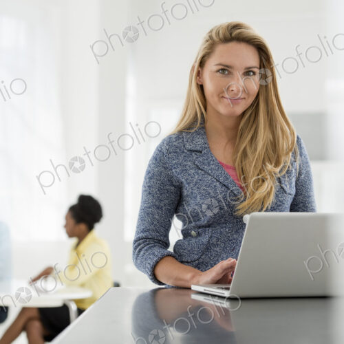 A fresh white building interior, flooded with light. A woman sitting at a table using… A fresh white building interior, flooded with light. A woman sitting at a table using…