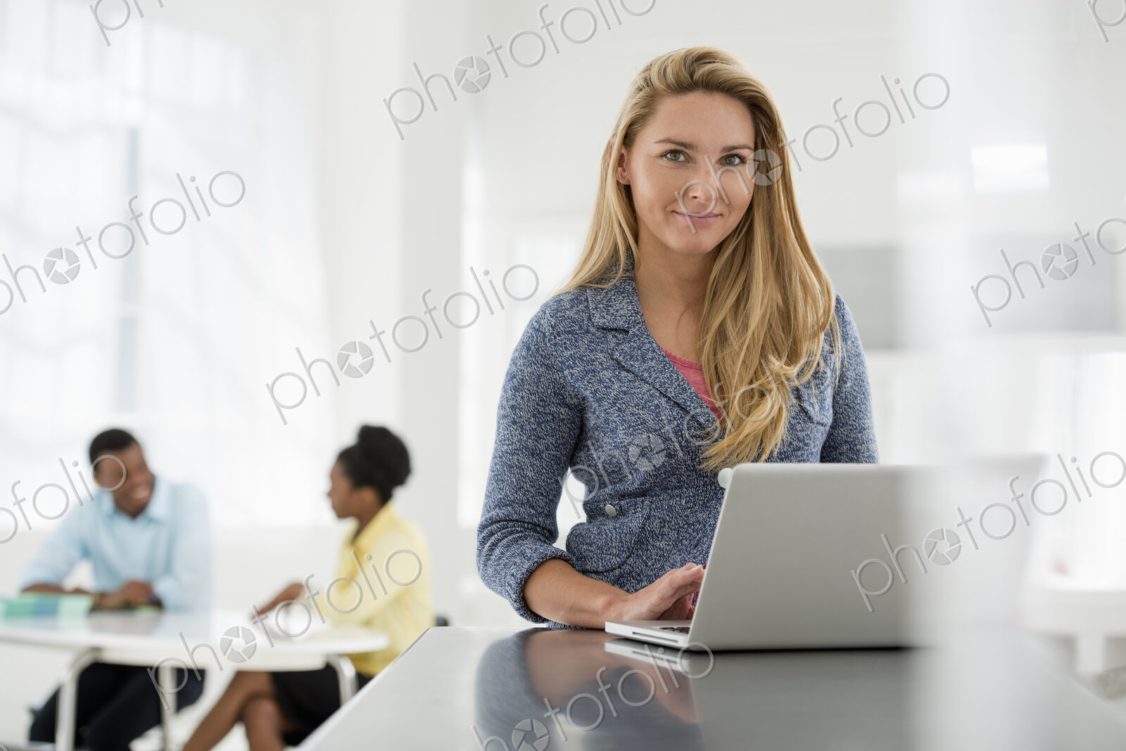 A fresh white building interior, flooded with light. A woman sitting at a table using…