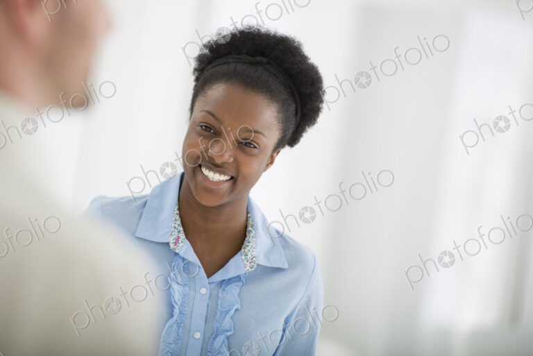 A fresh white building interior, flooded with light. A woman smiling and talking to a man.