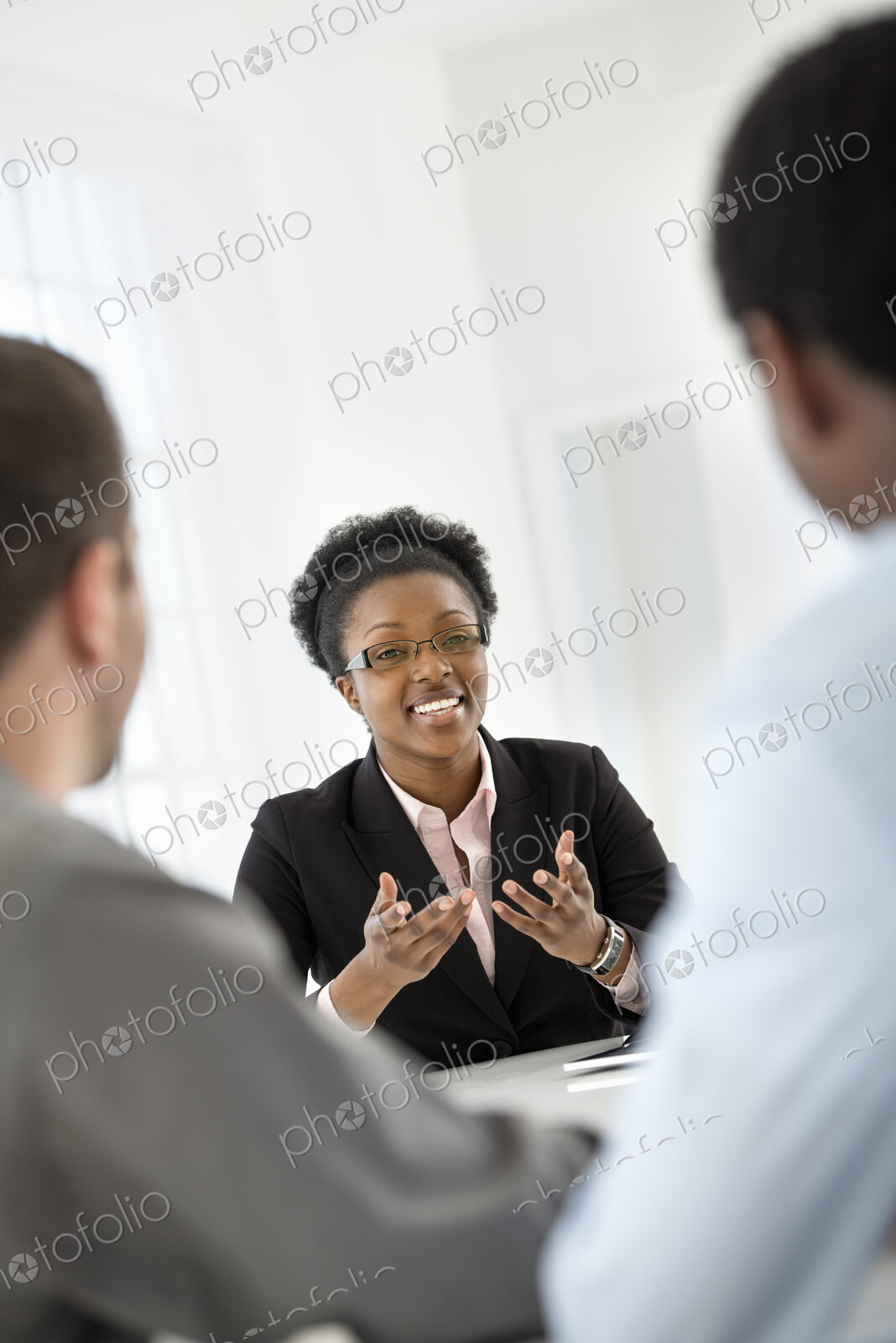 A fresh white building interior, flooded with light. Three people sitting around a…