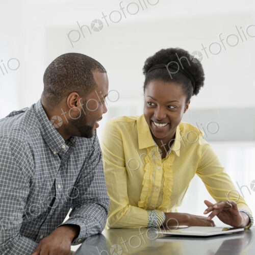 A fresh white building interior, flooded with light. Two people, a couple at a table…