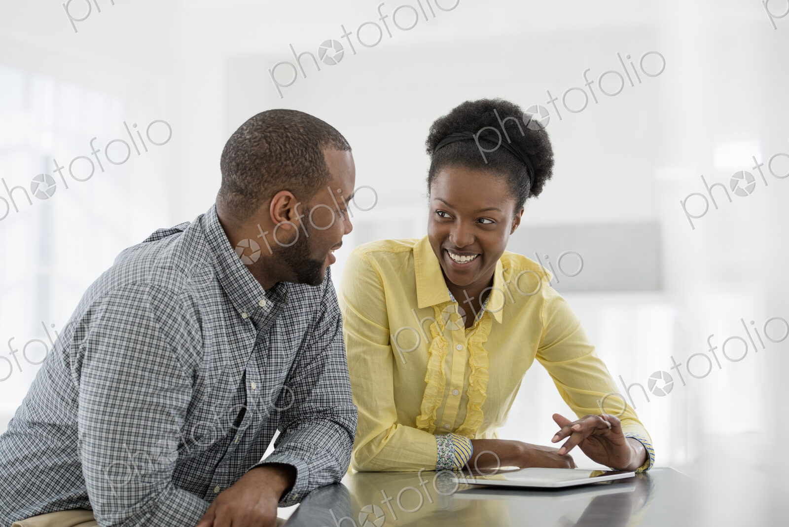 A fresh white building interior, flooded with light. Two people, a couple at a table…