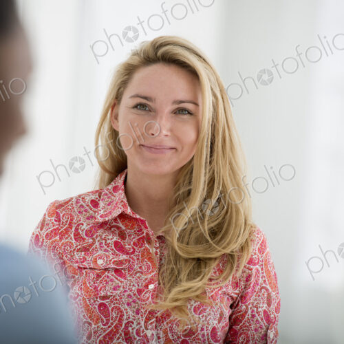 A fresh white building interior, flooded with light. Two people talking to each other.