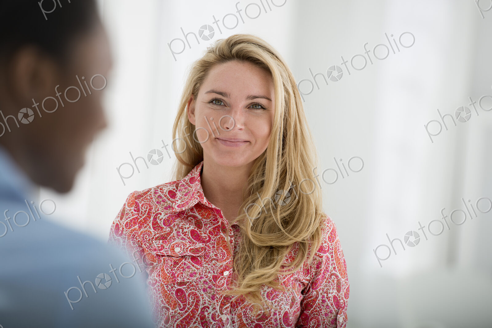 A fresh white building interior, flooded with light. Two people talking to each other.