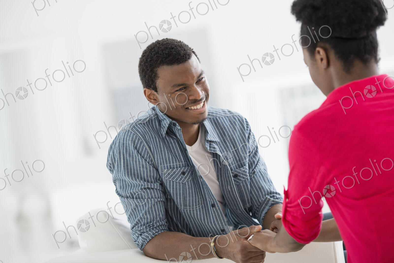 A fresh white building interior, flooded with light. Two people talking to each other,…