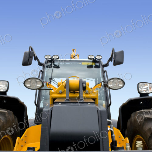 A frontal view of a new modern earth digger vehicle with yellow paint and a driver cab. A frontal view of a new modern earth digger vehicle with yellow paint and a driver cab.