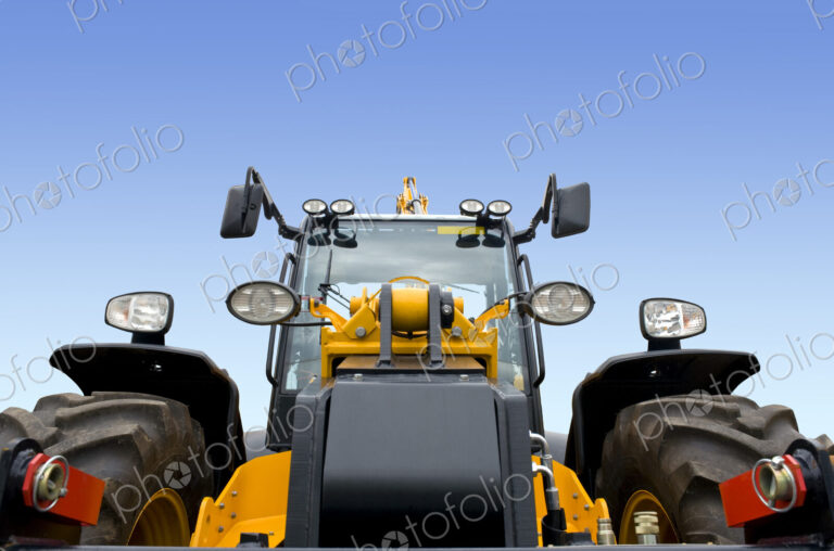 A frontal view of a new modern earth digger vehicle with yellow paint and a driver cab.