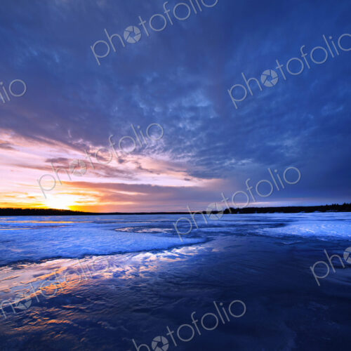 A frozen lake at dusk, and view to the setting sun on the horizon. A frozen lake at dusk, and view to the setting sun on the horizon.