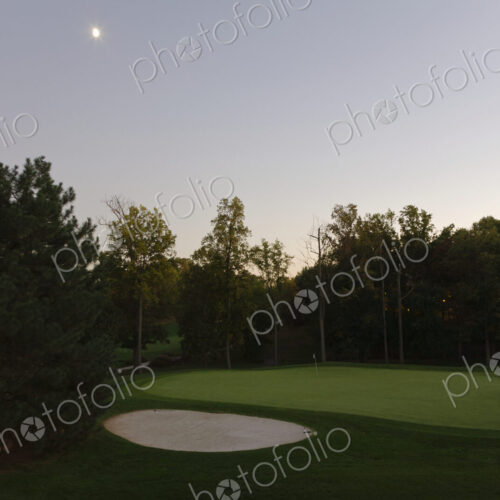 A full moon in the sky at dusk, hanging over a sand trap on a golf course. A full moon in the sky at dusk, hanging over a sand trap on a golf course.