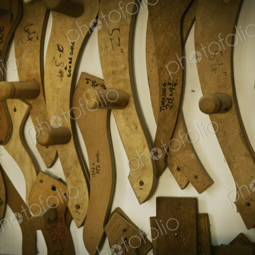 A furniture workshop, wooden chair arm rest templates hanging on the wall.
