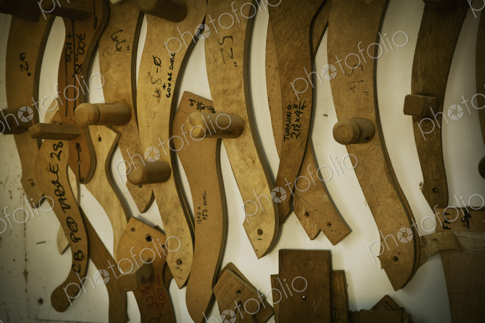 A furniture workshop, wooden chair arm rest templates hanging on the wall.