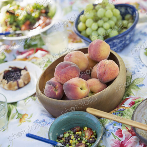 A garden table laid with a buffet of salad, fresh vegetables and fruit.