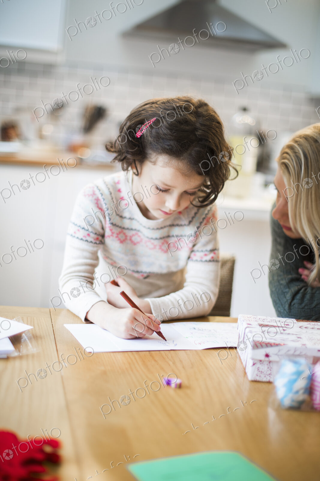 A girl at a table drawing in a card, a letter to Santa.