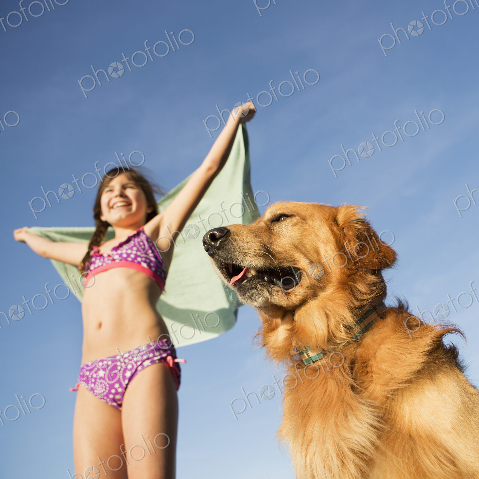 A girl in a beach towel with a golden retriever dog.
