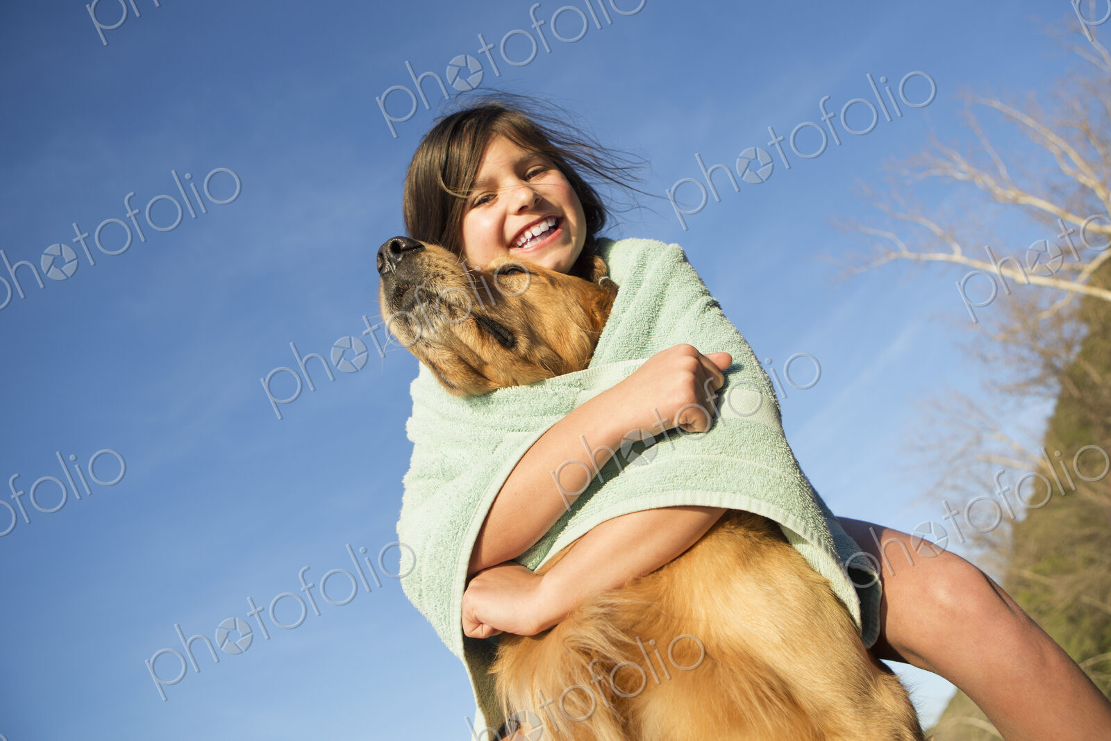 A girl in a beach towel with a golden retriever dog.