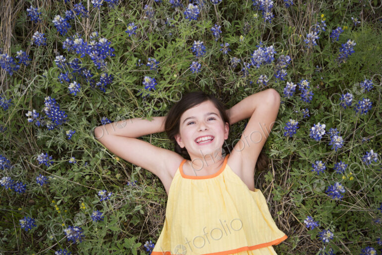 A girl lying on the grass amid wild flowers.