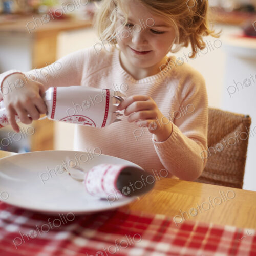 A girl opening a Christmas cracker at a table. A girl opening a Christmas cracker at a table.