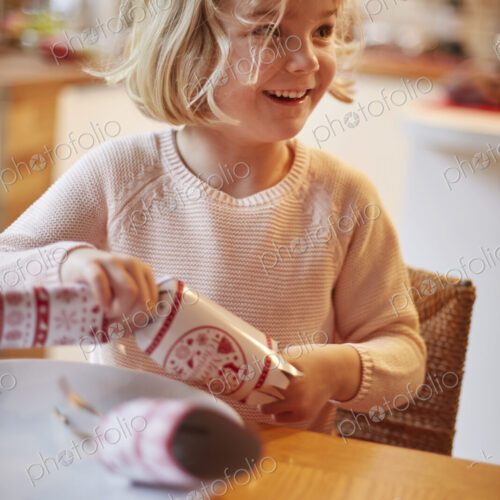 A girl opening a Christmas cracker at a table. A girl opening a Christmas cracker at a table.