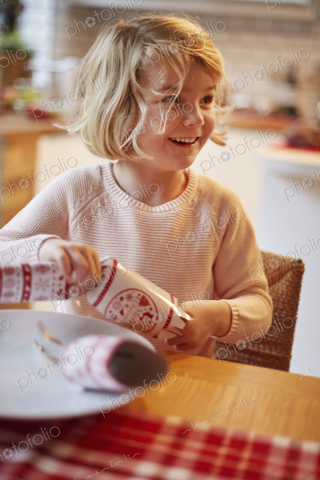 A girl opening a Christmas cracker at a table.