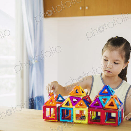 A girl playing, building a structure with colourful geometric shapes. A girl playing, building a structure with colourful geometric shapes.