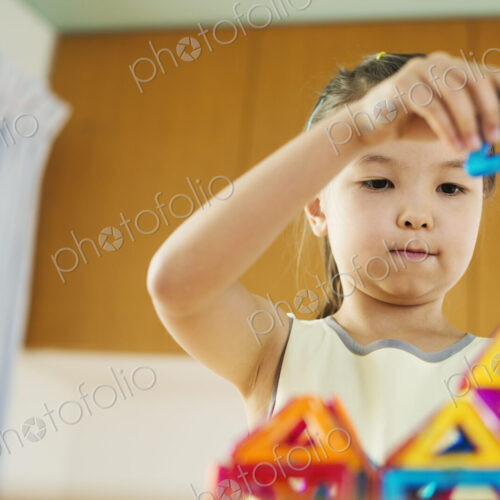 A girl playing, building a structure with colourful geometric shapes. A girl playing, building a structure with colourful geometric shapes.