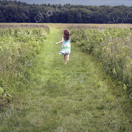 A girl running through a meadow in summer. A girl running through a meadow in summer.