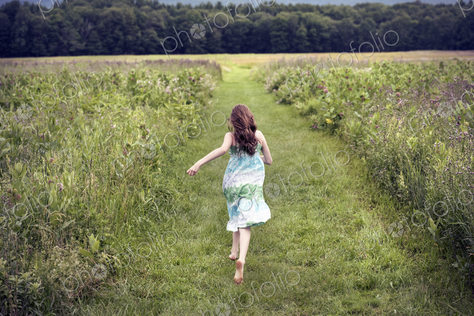 A girl running through a meadow in summer.